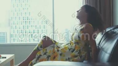 年轻漂亮的黑发女人在家里的皮革沙发上放松，看电影吃<strong>苹果</strong>。 3840x2160